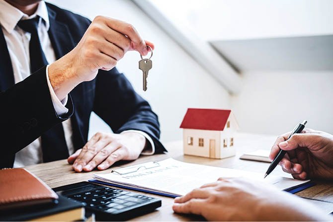 Estate agent giving house keys to client after signing agreement contract real estate with approved mortgage application form, concerning mortgage loan offer for and house insurance 